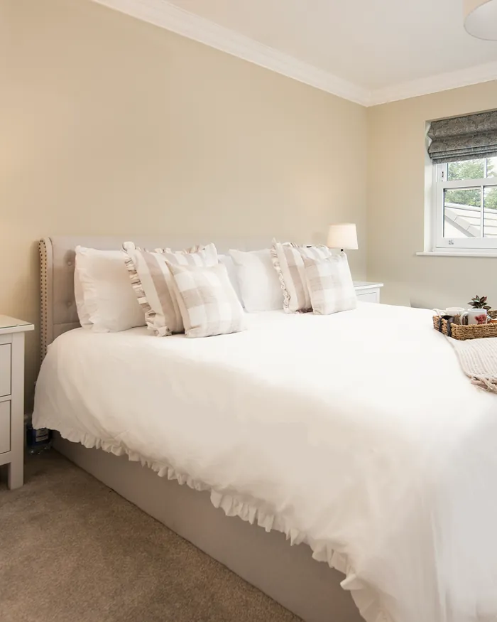 Bedroom with ruffled white bedding and checked cushions