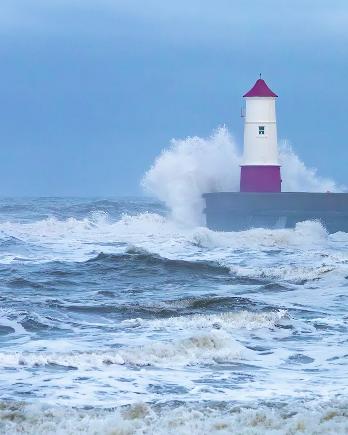 Waves breaking against Berwick lighthouse at the end of the pier
