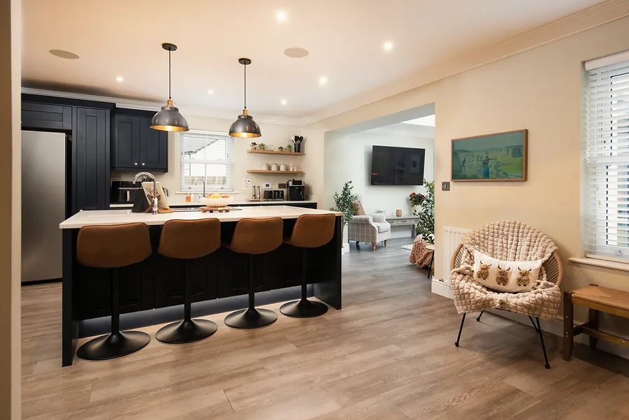 Kitchen with a dark island, bar stools and pendant lights